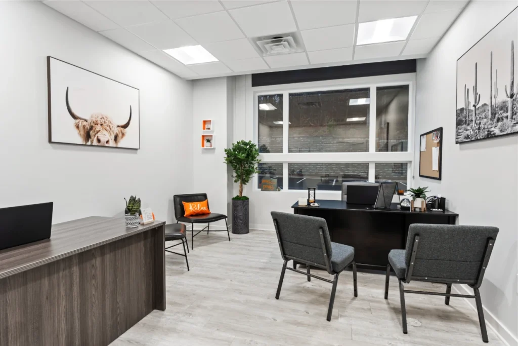 Harmony Recovery Center modern office waiting area with gray chairs, white walls, large windows, potted plants, and contemporary lighting fixtures