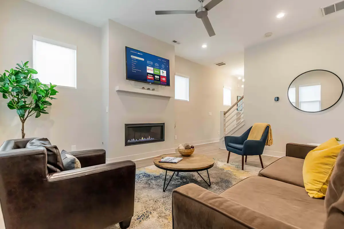Harmony Recovery Center contemporary living room featuring brown sectional sofa, modern fireplace, wall-mounted TV, round coffee table, and neutral color scheme
