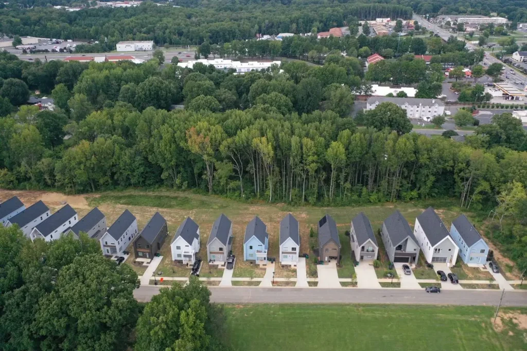 Harmony Recovery Center aerial view of residential development showing row of modern houses with dark roofs surrounded by green forest and trees